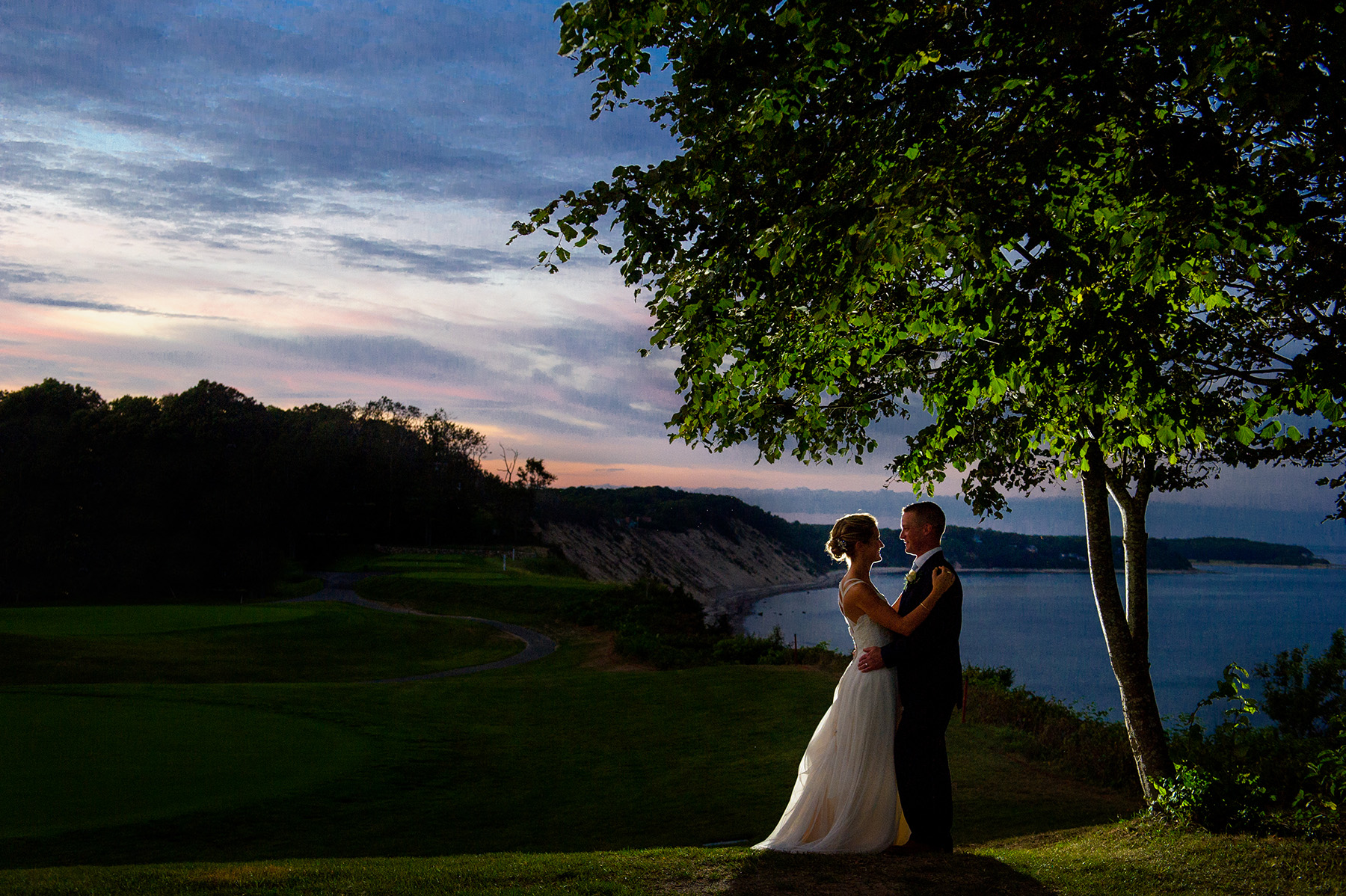bride and groom pose against a summser sunset at White Cliffs CC