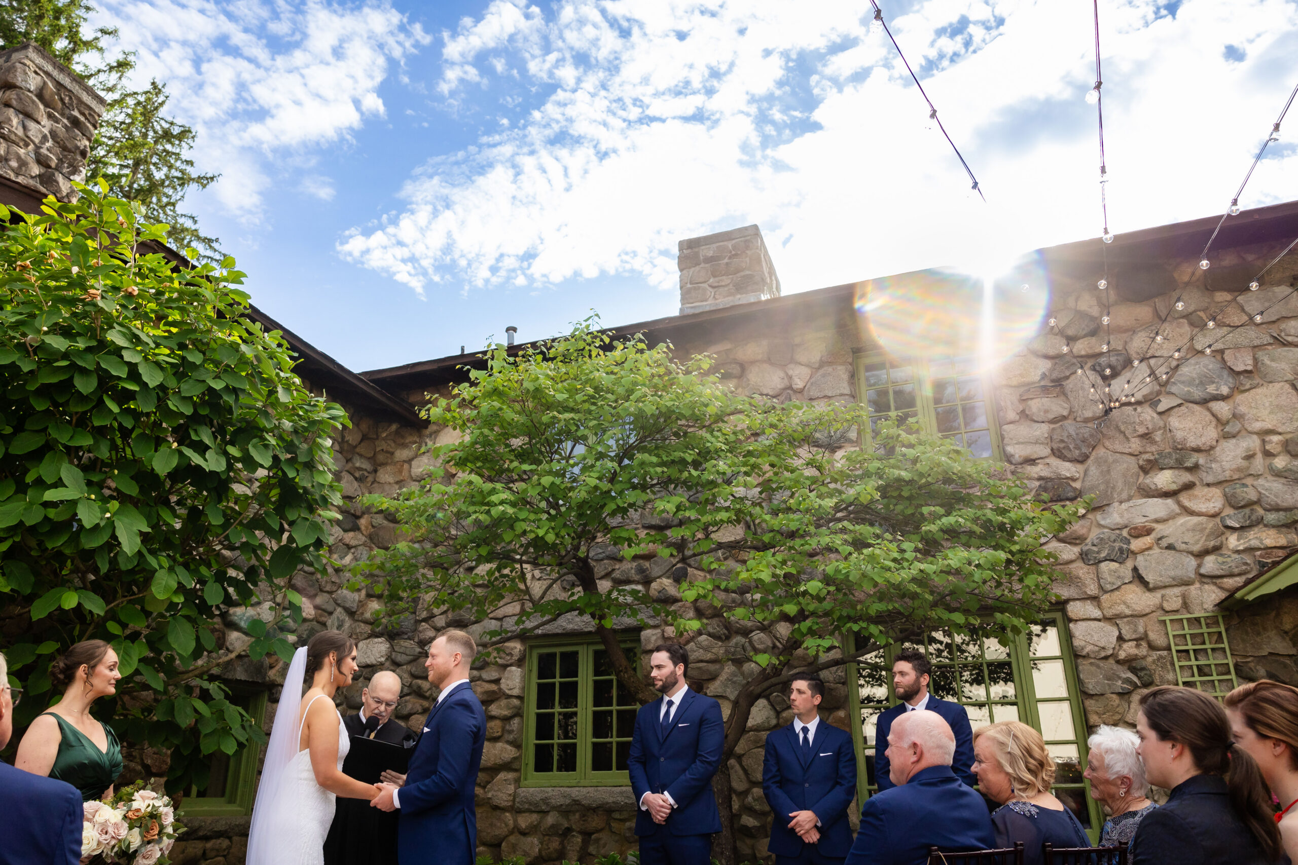 couple exchanges rings under blue sky at Willowdale Estate